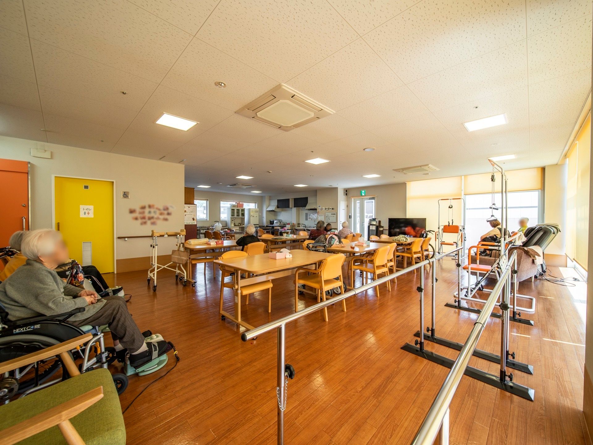 食堂のテーブルの周りには、黄色の背もたれとひじ掛けがついた椅子が置かれている。天井埋め込み式のエアコンが２台設置されている。