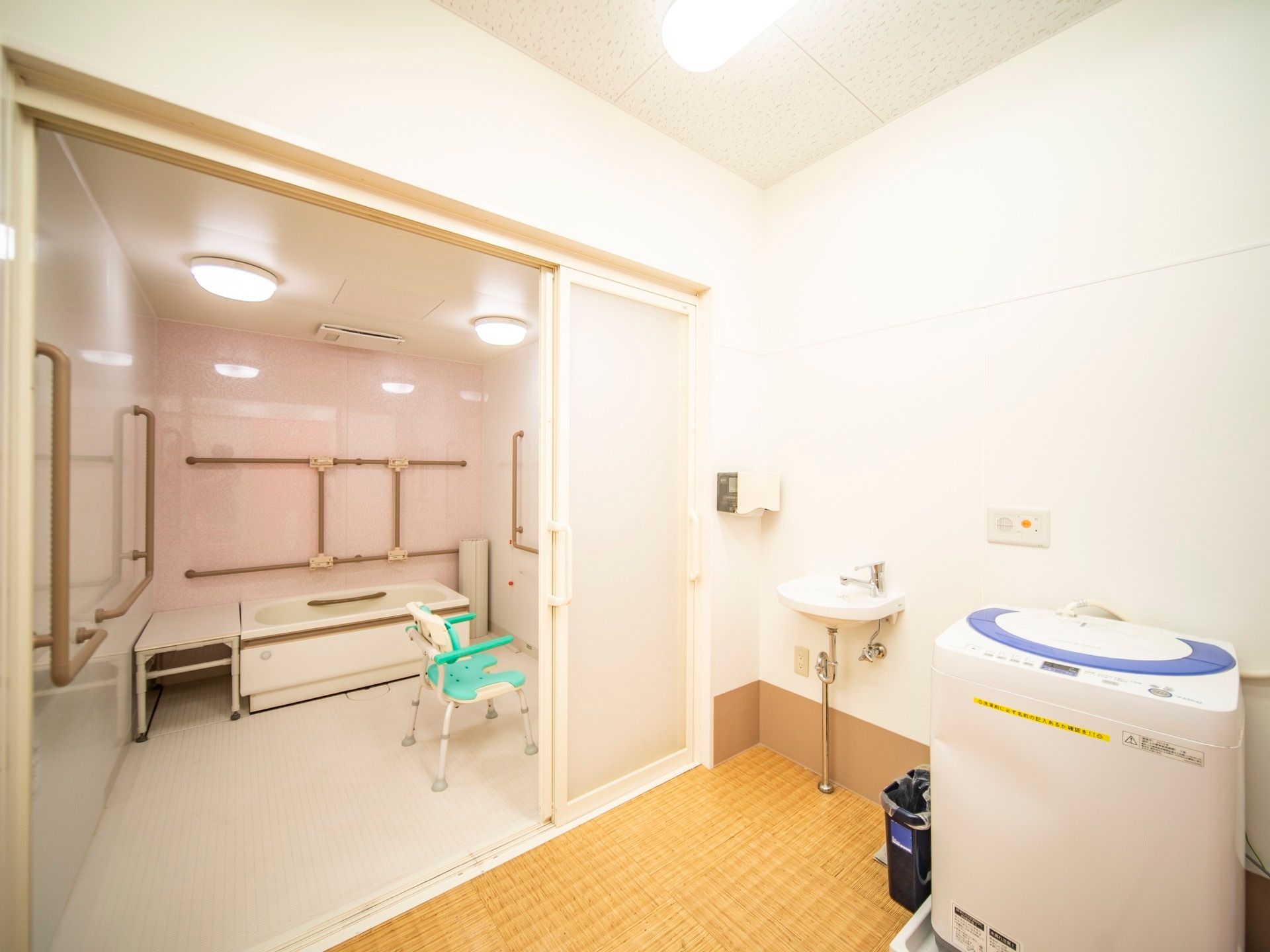 浴室入口は、大きな取っ手がついた引き戸になっている。脱衣所には、洗面台と自動洗濯機が設置されている。