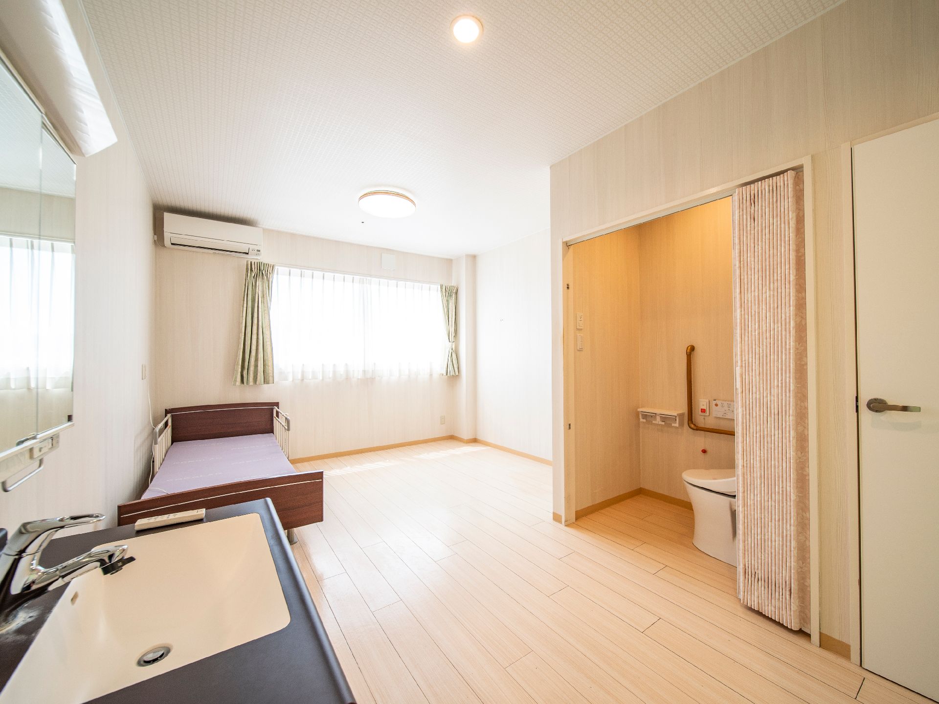 手前にキッチンがあり、向かいにアコーディオンカーテンで仕切られたトイレのある部屋