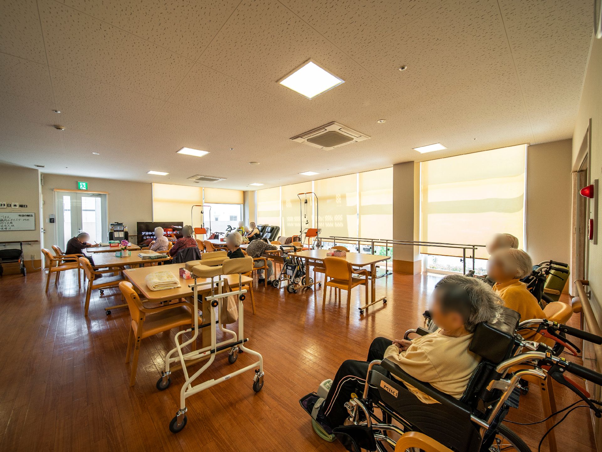 レールカーテンが下がった共有スペースに集まってテレビを見ている入居者様