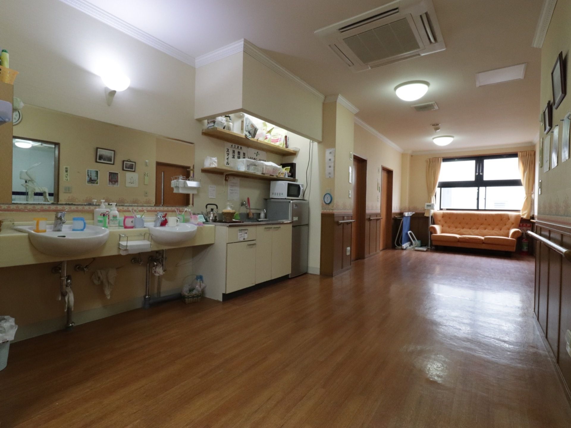 広く落ち着いた雰囲気の廊下である。洗面台を設置しており、手軽に手を清潔に保つことができる。手すりがあるので、安全に移動することができる。