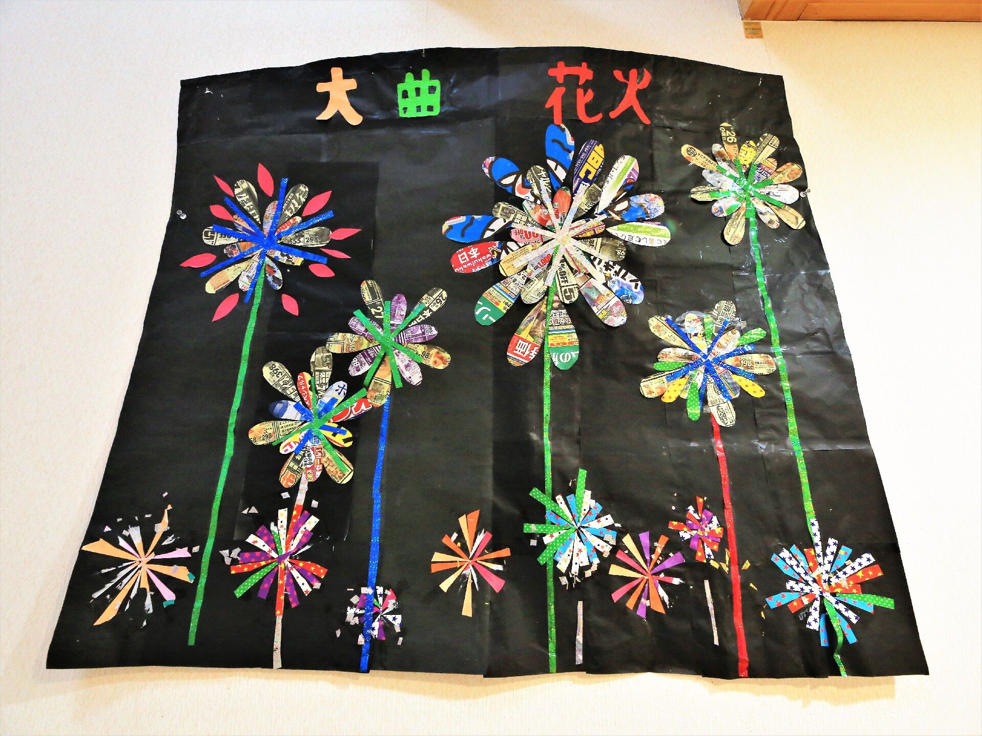 黒い紙にカラフルな広告を切って作られた地元の花火の作品