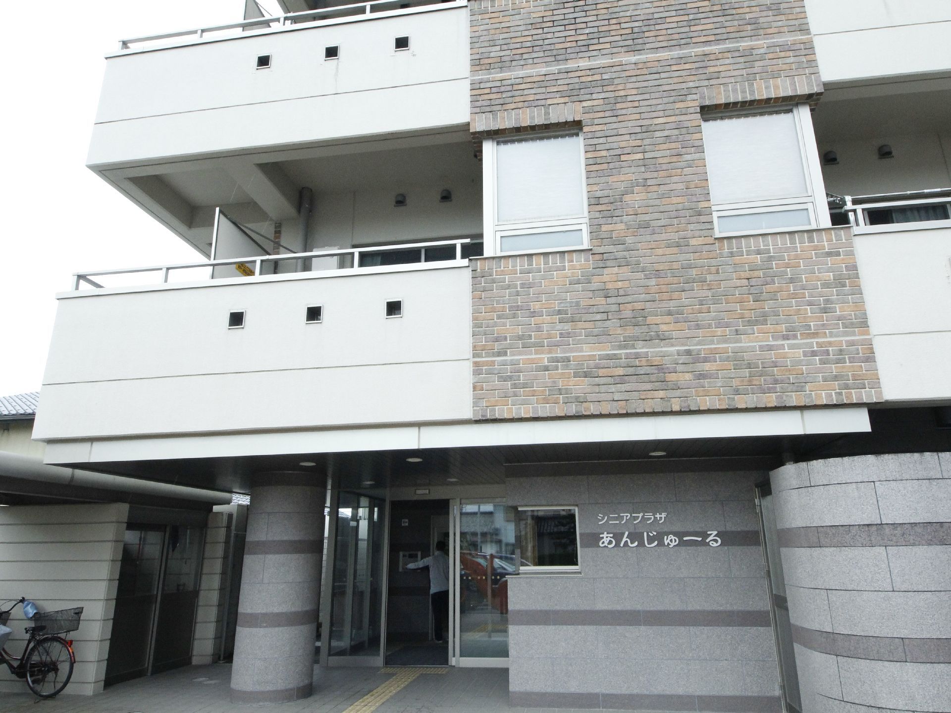 施設は集合住宅のような外観。外壁に施設名が書かれている。入口までのアプローチには点字ブロックがある。