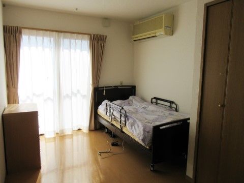 介護用ベッドの横にベランダへ続く大きな窓がある部屋