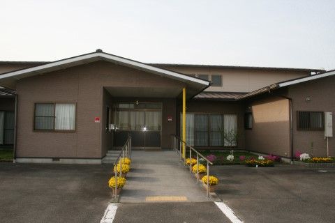 玄関に向かって黄色い花が咲いたプランターが置かれている入口