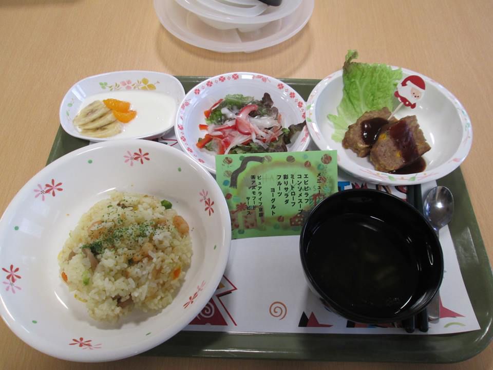 緑色のトレイに並んだ、エビピラフやミートローフなどの洋風の食事