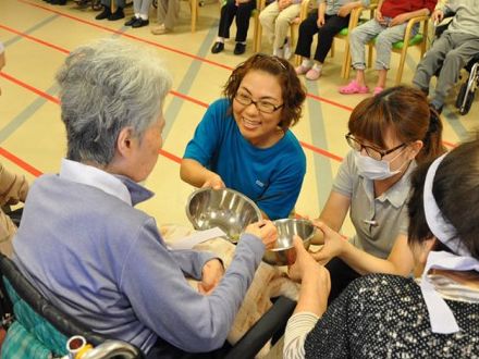 車椅子に乗って、スタッフがさし出したボールに手を出す入居者様