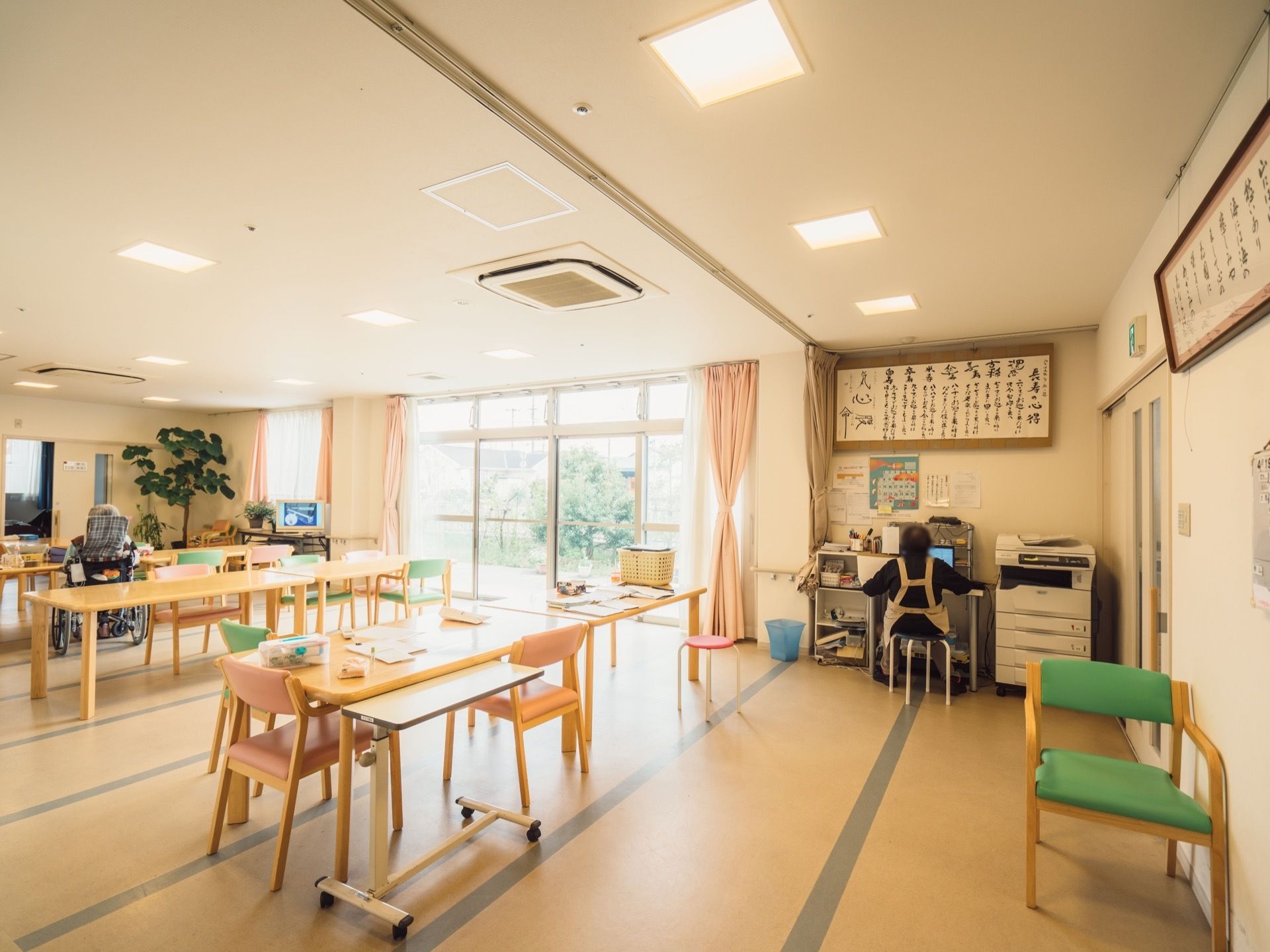ダイニングテーブルと椅子がセットでいくつも用意されている。スタッフがパソコンで作業しているのが見える。