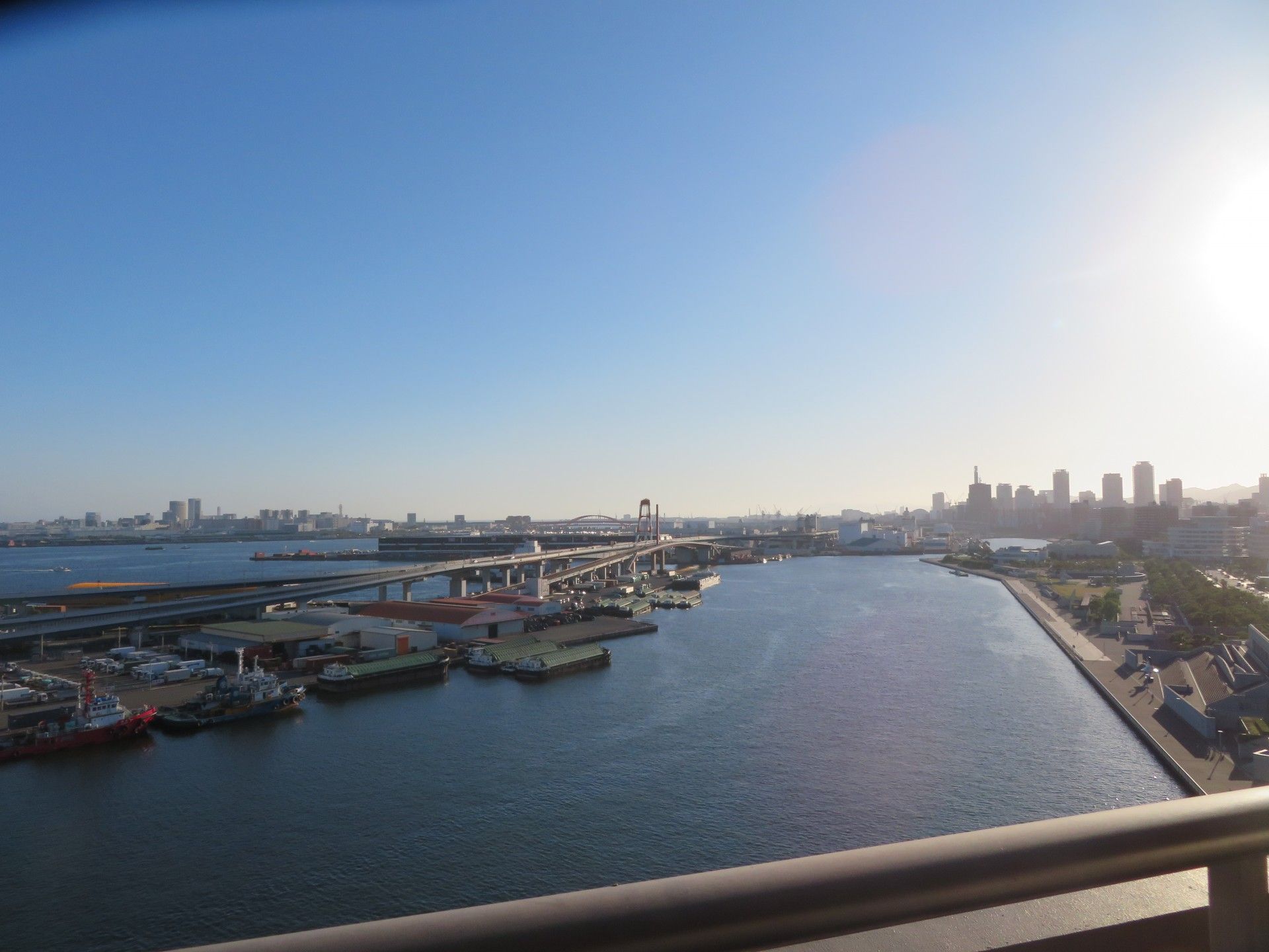 物干し竿が掛けられるようになっているベランダである。海が広がり、奥には高速道路や高層ビルなどが見える。