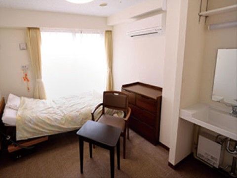奥の窓の前に布団が敷かれたベッドが置かれている１人用の部屋