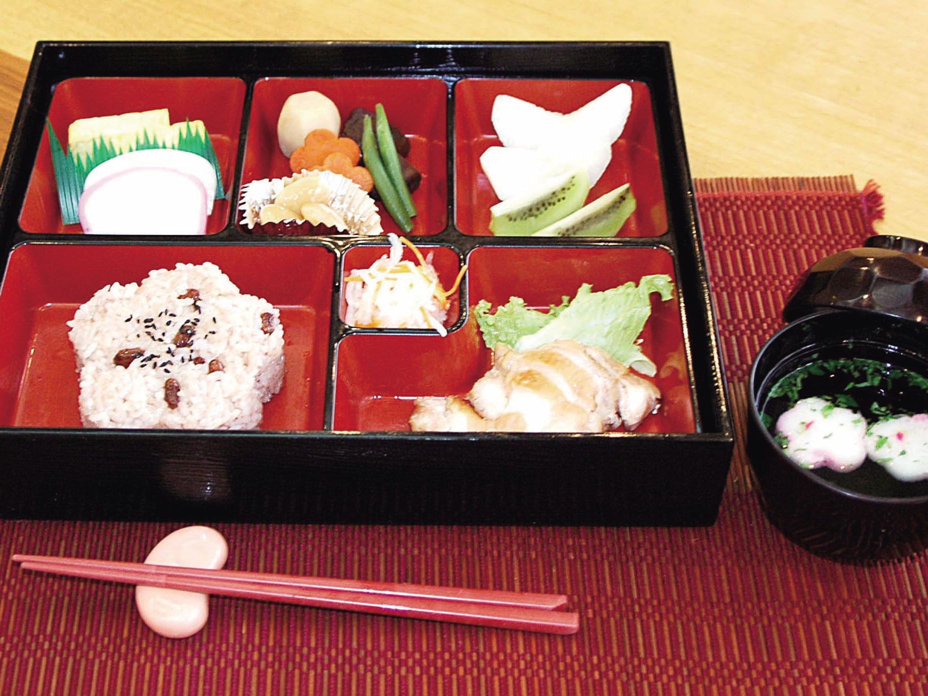 お赤飯や野菜の煮物などが並べられた松花堂風の器で出される食事