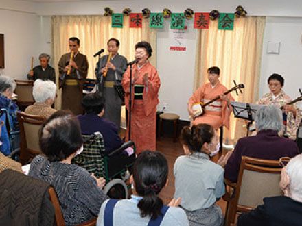 着物を着た人達が演奏する三味線を見学している入居者様