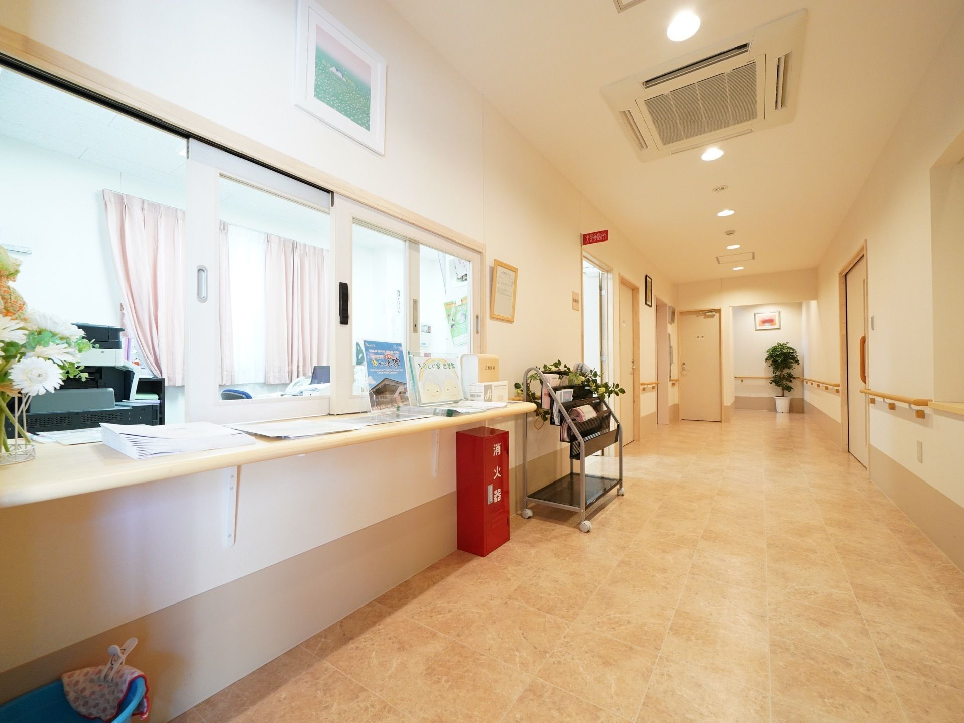 幅の広い廊下には、手すりが随所に設けられている。受付は明るく、花が飾られている。事務室が隣接されている。