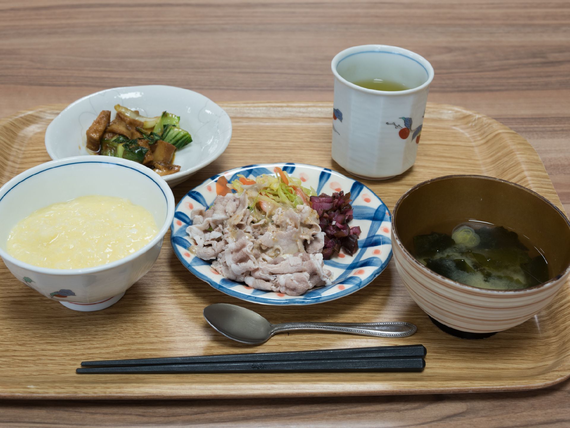 食事は一人ずつお盆にのせて配膳される。主食のご飯にお味噌汁、お肉のおかず、小鉢など、野菜や海藻を使ったメニューである。