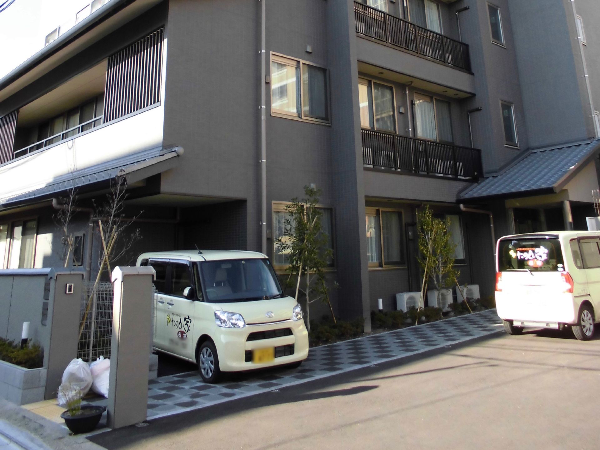 施設で保有している自動車が２台停められている施設の外観