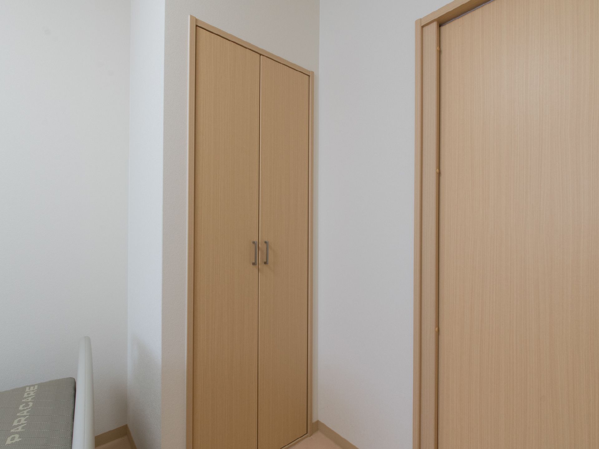 正面には木目調の両開きの扉があり、その右側にも同じようなものがある。左側にはベッドが置かれている。周囲の壁は白色になっている。