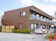 ダークブラウンの外観で重厚感がある。2階手前側はバルコニーになっており、各居室を間仕切壁で仕切ってある。