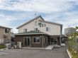 茶色と白色の外壁に、施設名ロゴと屋根が緑色の施設外観は周辺環境にとても馴染んでいる。駐車場から入り口まで広々した空間。