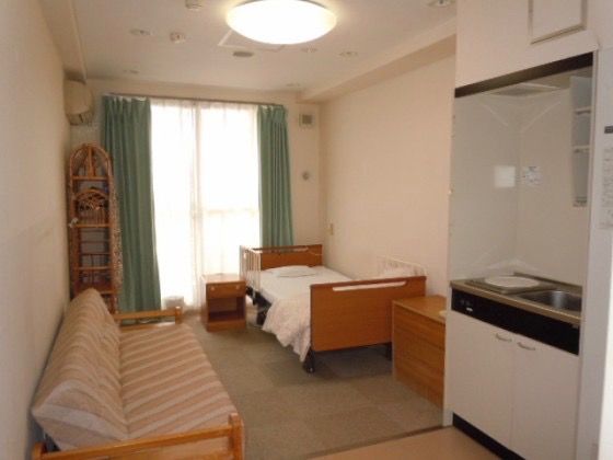 小型のキッチンを備え付けている、ソファとベッドが置かれた部屋