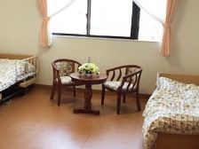 寝室をベッドの足側から写した写真。ベッドが２台置かれており、向かって左のベッドには転落防止の柵が設置されている。