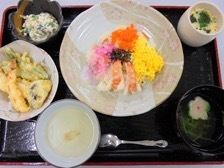 和食の一例である。中央に色鮮やかなちらし寿司があり、その周りに汁物や茶碗蒸し、天ぷら、小鉢、デザートが並べられている。