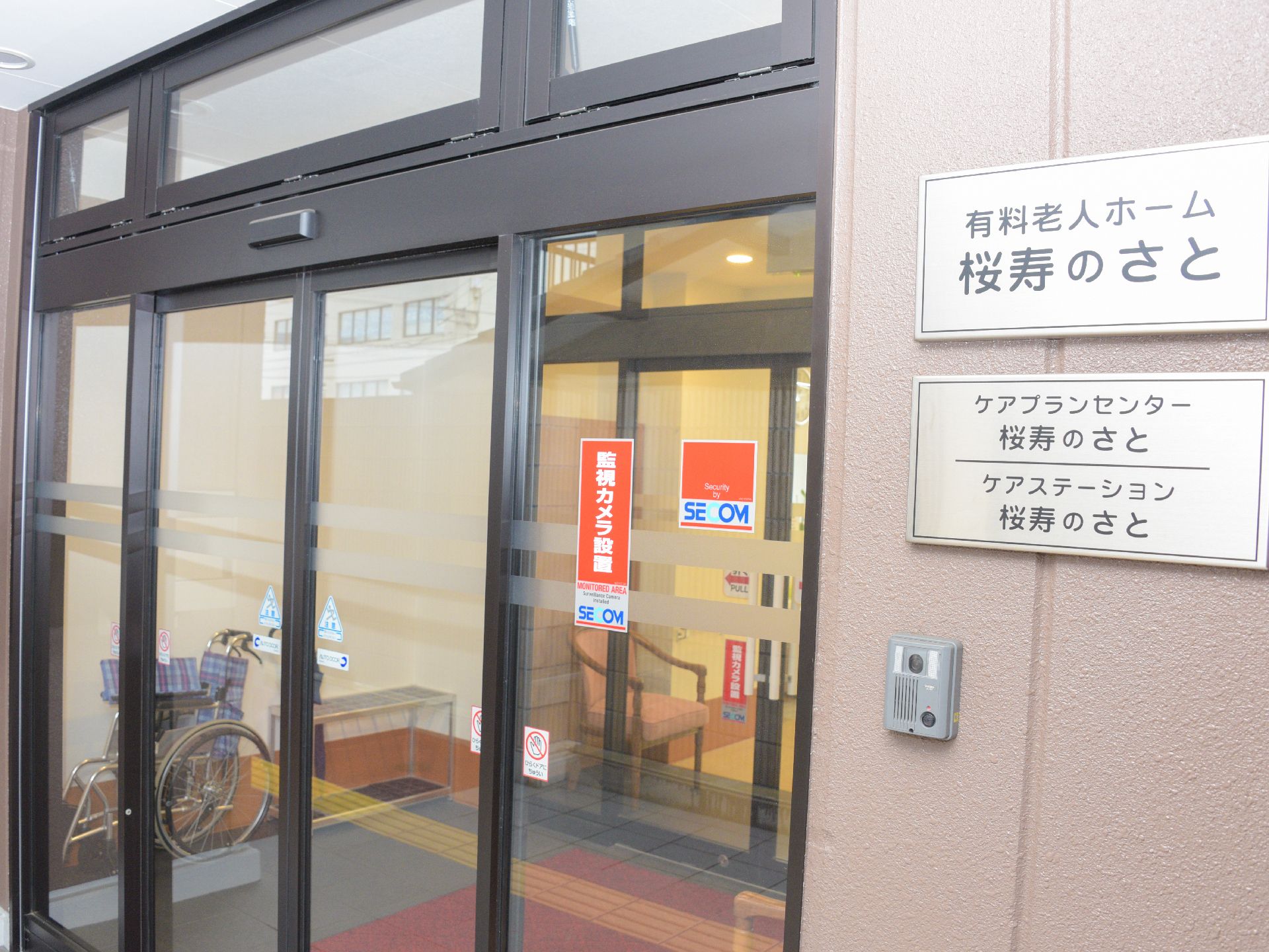 玄関は、自動ドアで車椅子利用者も出入りしやすくなっている。玄関の横には、施設の銘板が掲げてあり、来訪者にも分かりやすくなっている。
