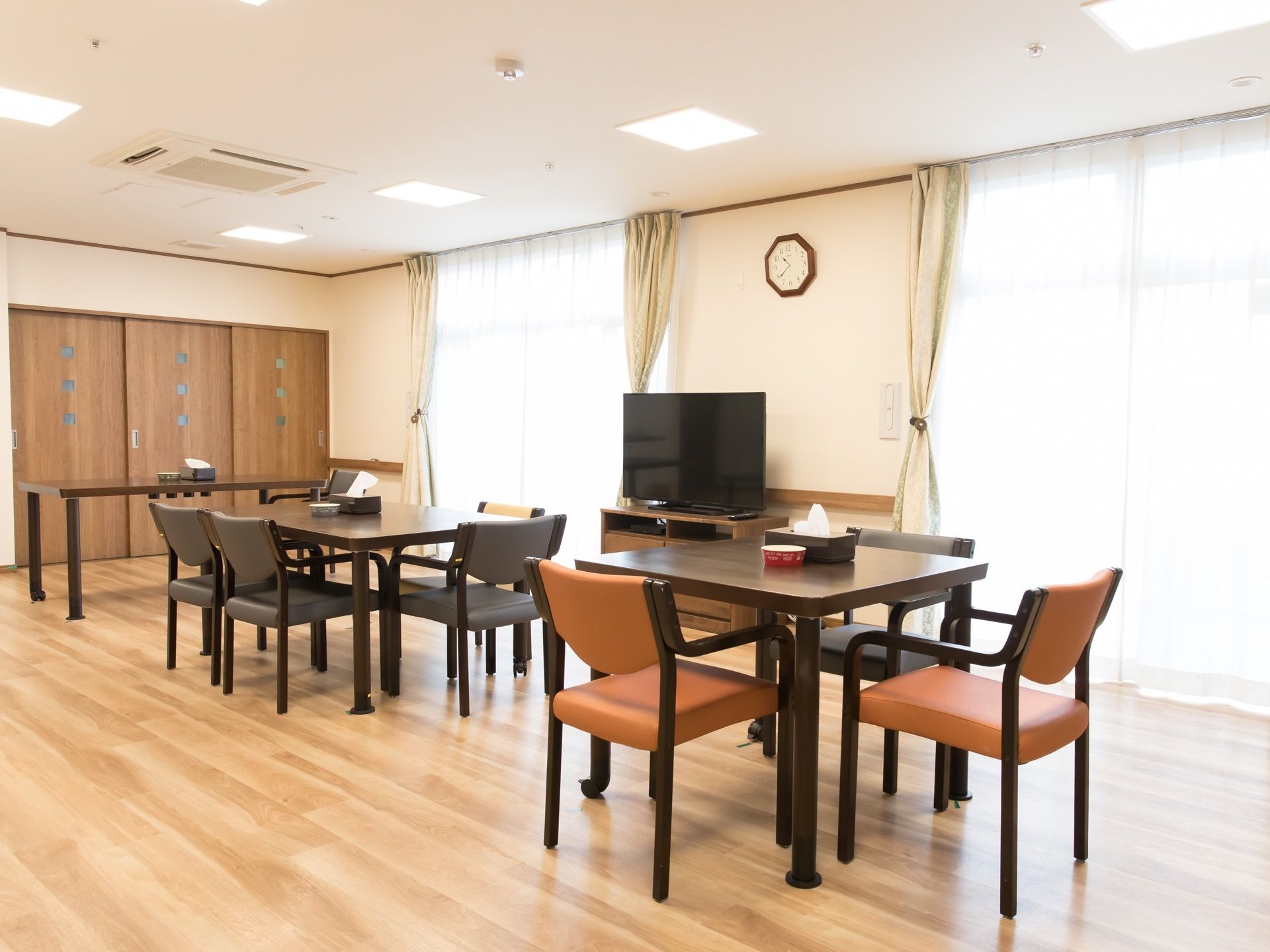 焦げ茶色の家具で統一された落ち着いた雰囲気の食堂である。窓際にはテレビが１台設置されており、カーテンは黄色系である。
