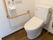 トイレには洋式便器が設置されている。壁にはトイレットペーパーフォルダーや水洗ボタン、呼び出しボタンがある。