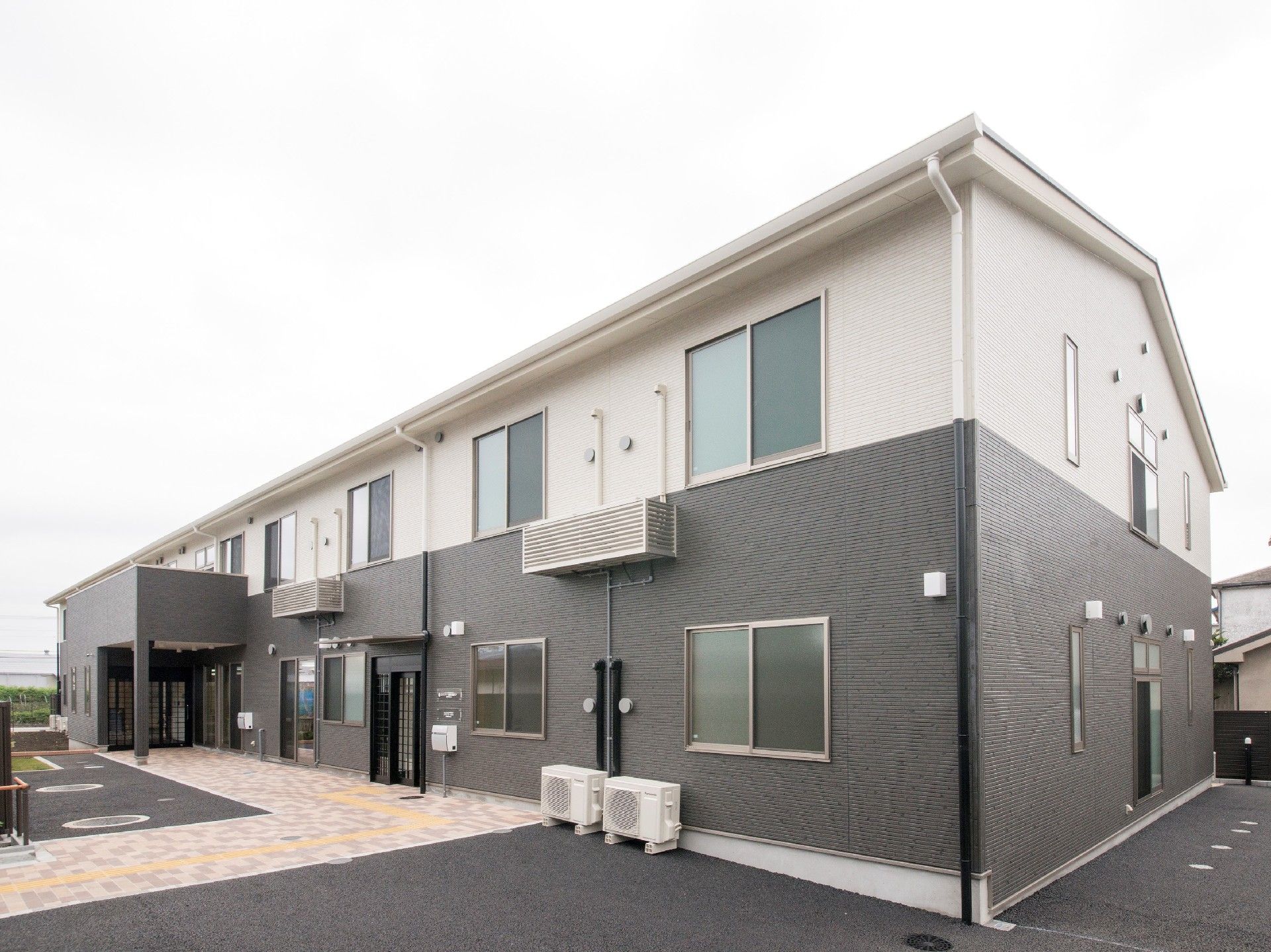 2階建ての建物にはたくさんの窓が付き、玄関が二つあり、それぞれに屋根が付いている。
