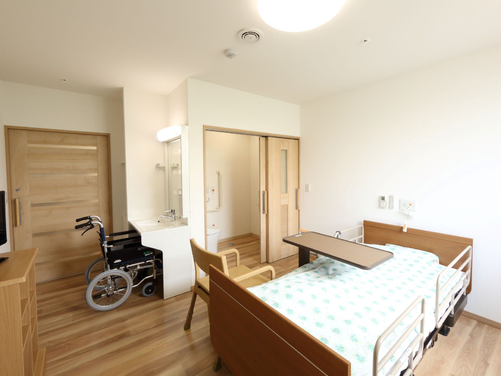 寝具付きのベッドが中央に置かれたフローリングの居室には、洗面所やトイレも付いている。