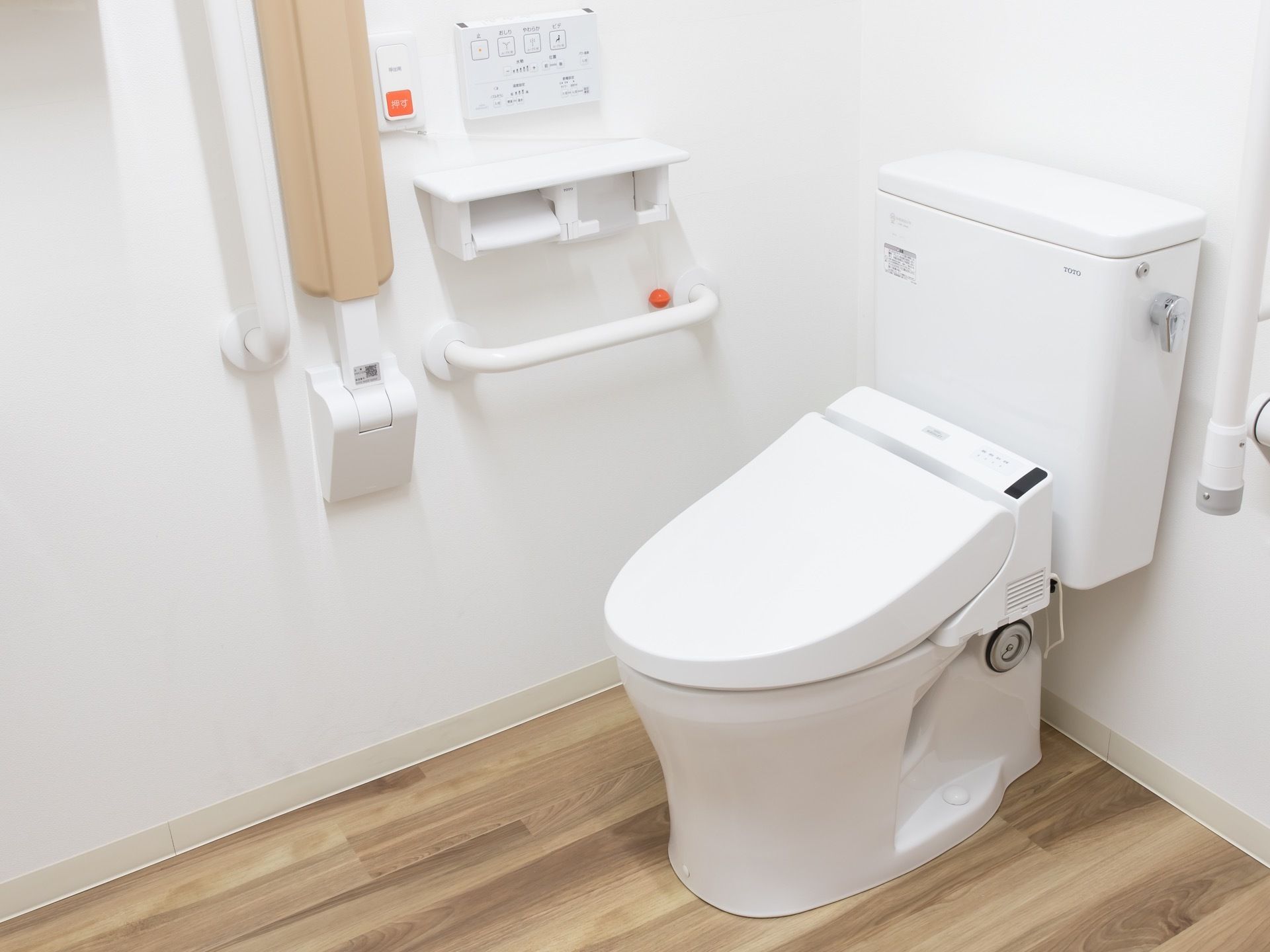 洗浄機能付きの暖房便座トイレで、壁には手すりや呼び出しベルが取り付けてある。ペーパーホルダーは２つ設置してある。
