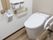 清潔感がただよう白が基調のトイレである。温水洗浄便座や手すりのほか、ペーパーホルダーが２つ完備されている。