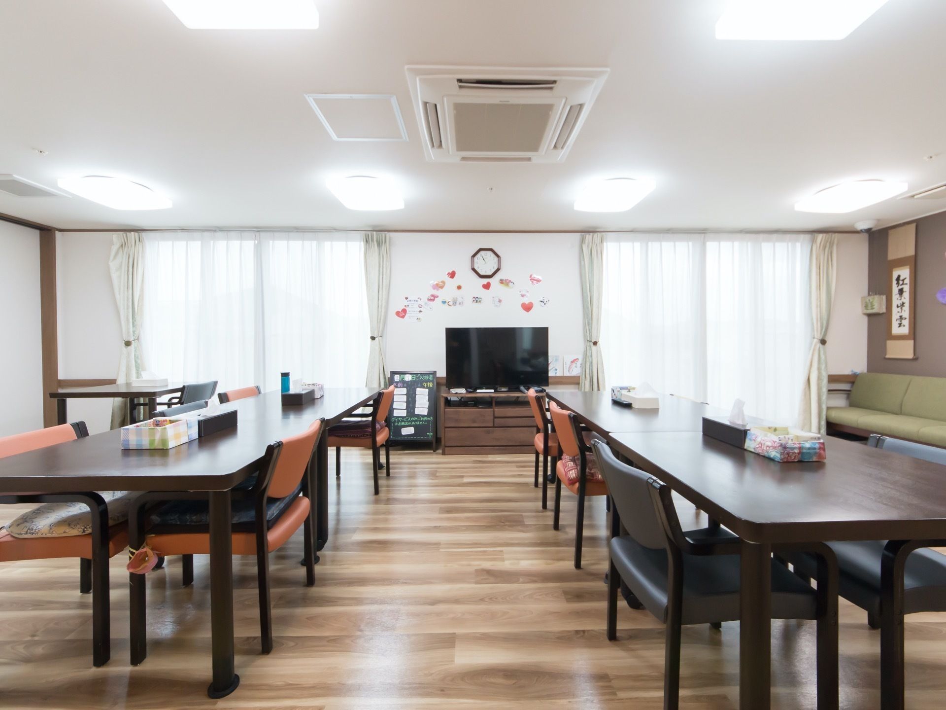 窓からの日射しとLEDライトで照らされた明るい食堂である。部屋の中央に大型液晶テレビが置かれているので、どの席からでも観ることができる。