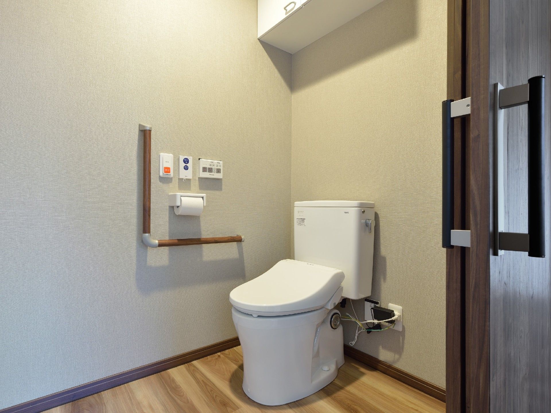 呼び出しボタンがついたトイレにはエル字型の手すりがあり、フローリングのフロアで介助スペースも広い。