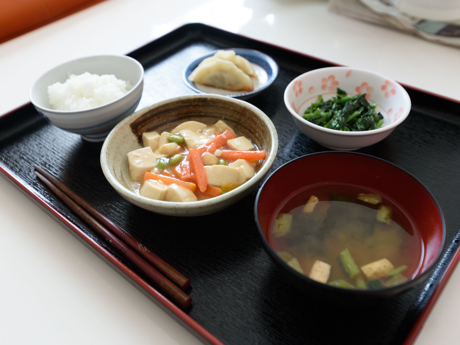 黒いお盆の上にバランスのとれた食事が置かれている。手前には箸が用意されている。料理は刻まれておらず、常食となっている。