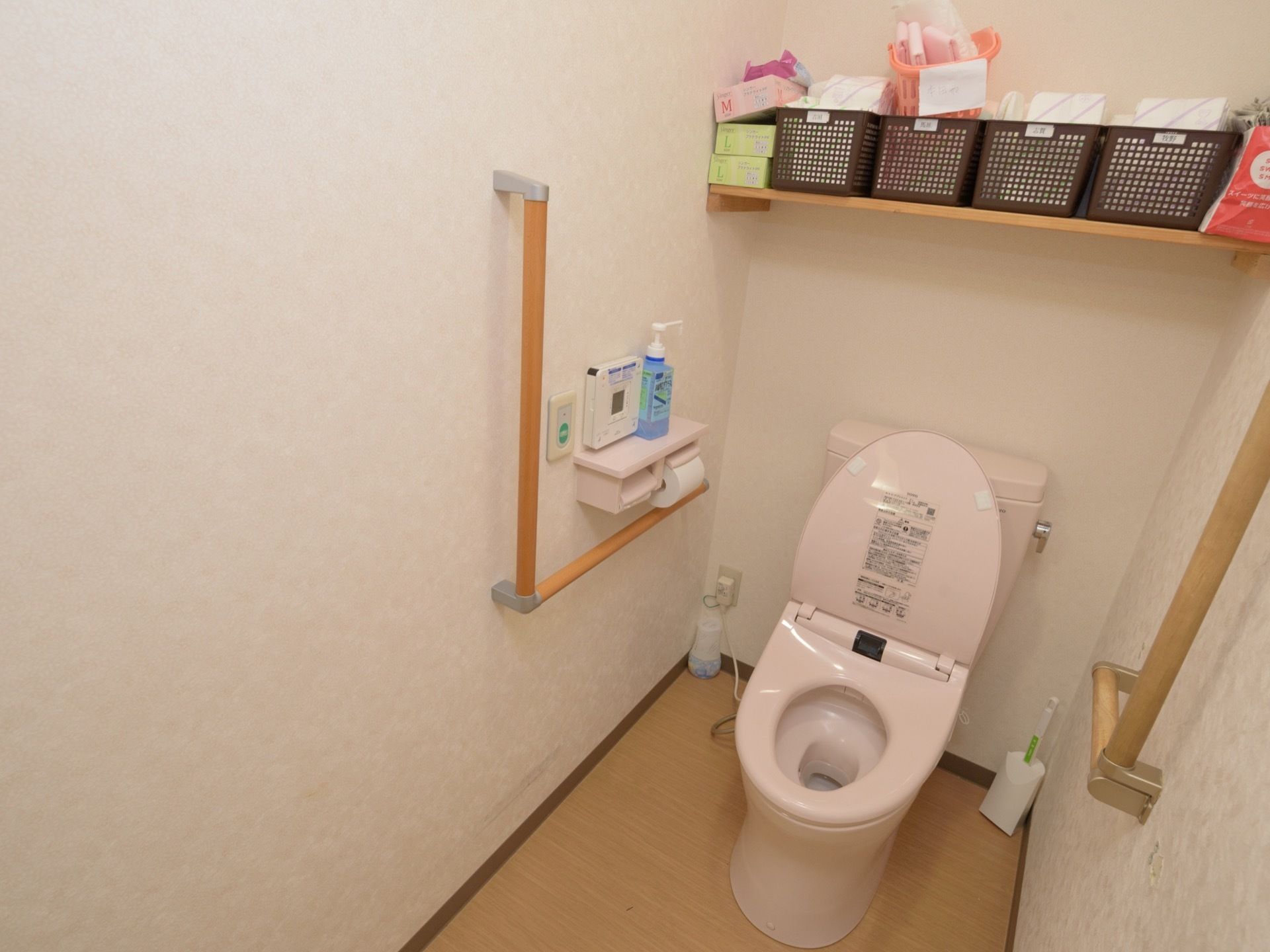 トイレの上にある棚には入居者様の備品を置いている。トイレの周りに手すりを設け、立ち上がりやすくしている。