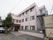 淡いピンク色の外観で3階建てとなっている。大きな木が立っている。建物の横には駐輪場が設置されている。