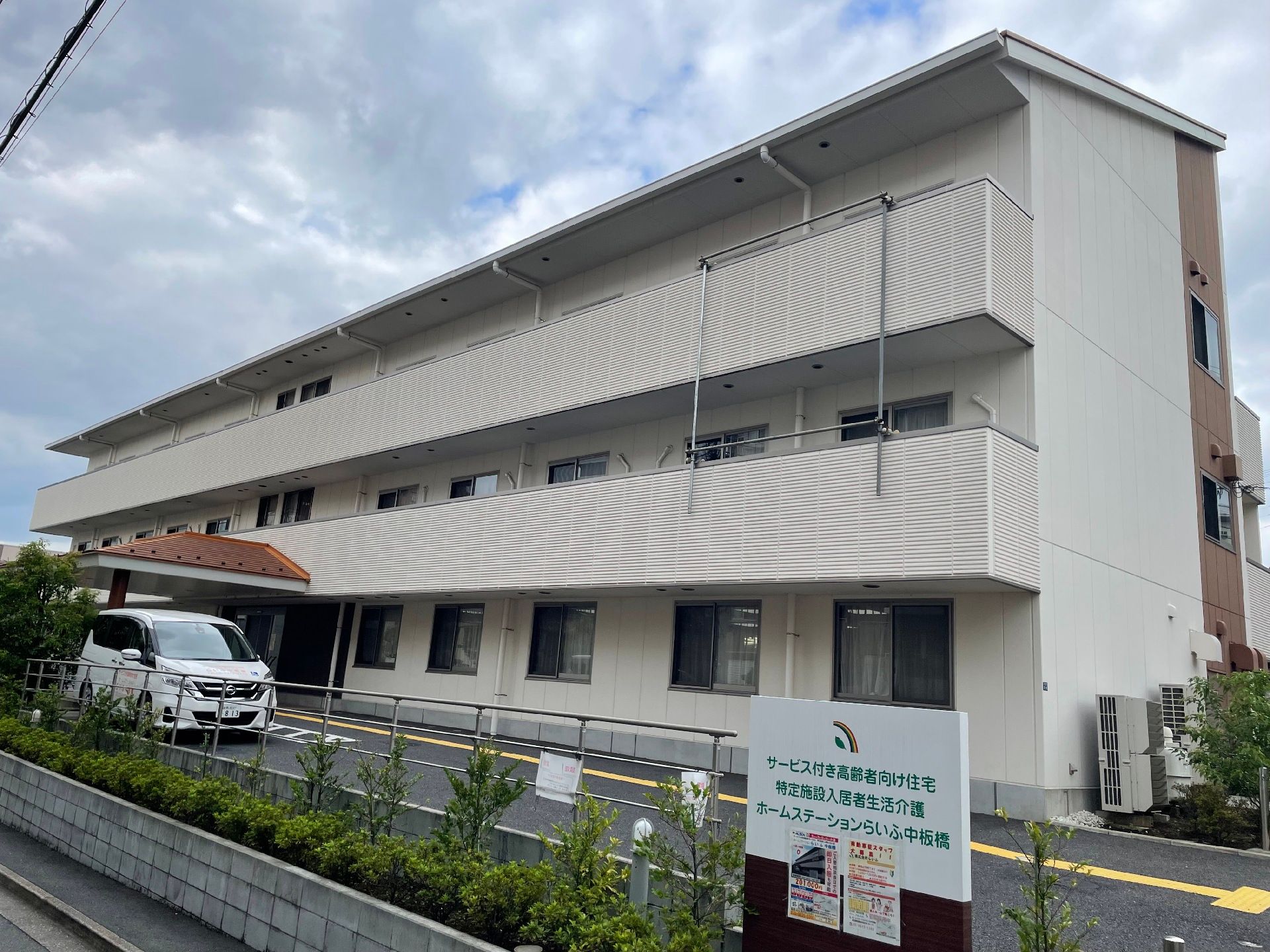 ３階建ての建物で、外壁の色はベージュ系になっている。屋根付きの玄関の両側にはスロープが設置されている。