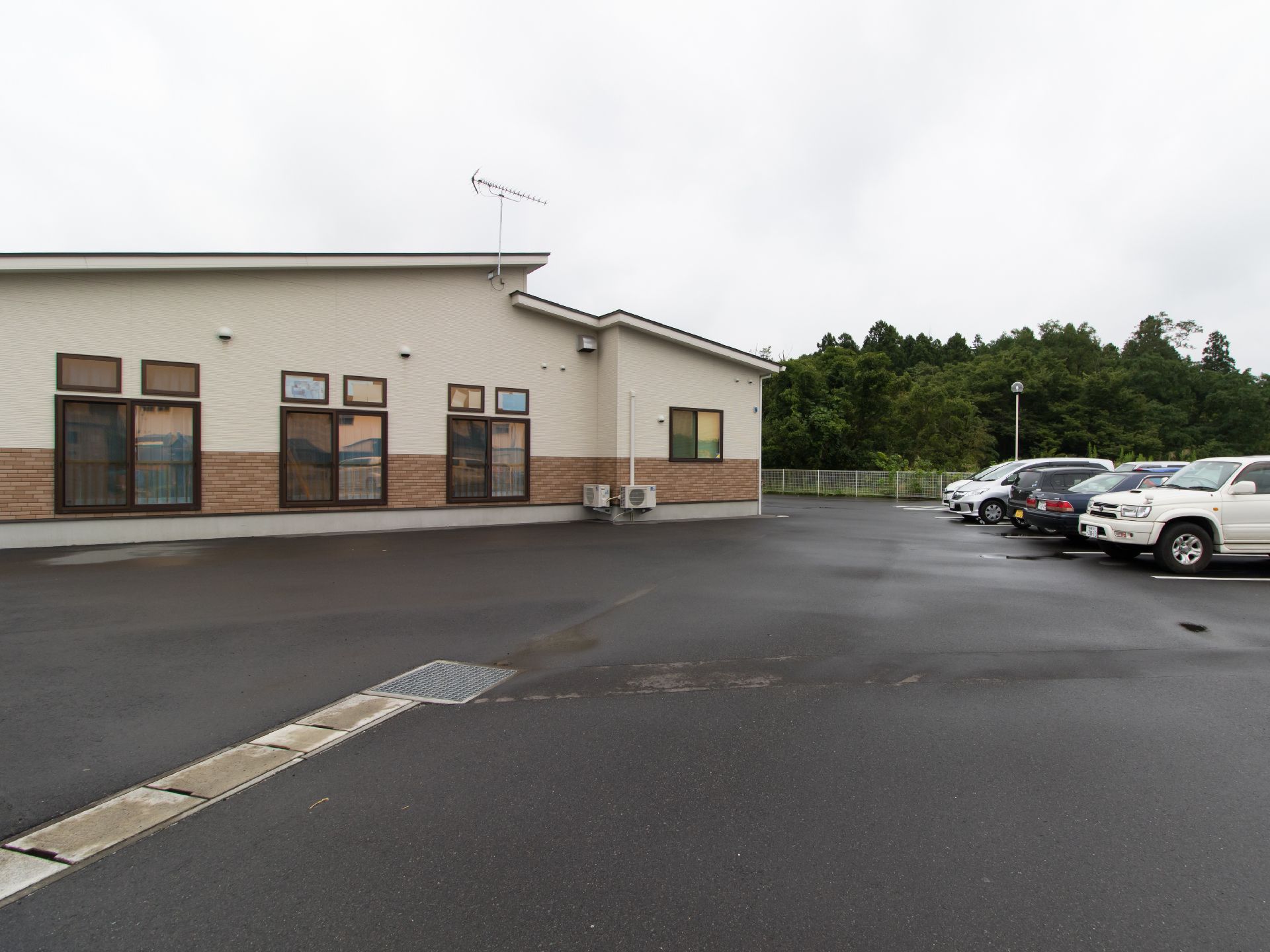 施設の外観である。建物の横には、広い駐車場が完備されている。施設の窓にはスモークが使われていて、外から中が見えないようになっている。