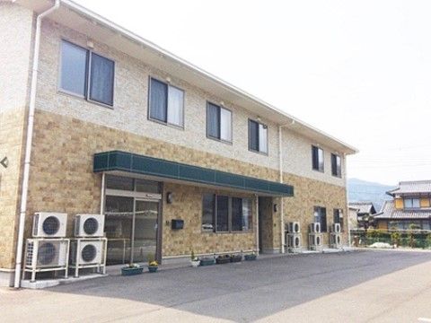 建物は２階建てで、ナチュラルな優しい雰囲気の外観となっている。敷地が広いので、車を停めるスペースが十分にある。