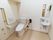 温水洗浄機能付き便座が採用されているトイレである。壁にはＬ字型の手すりや操作パネルが設置されている。