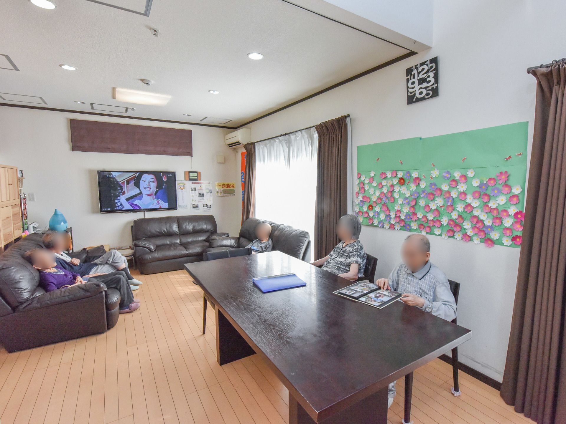 床は、明るい木目調のフローリングである。リビングには、ブラウンのソファーが置かれており、ダイニングにはブラウンのテーブルが設けられている。