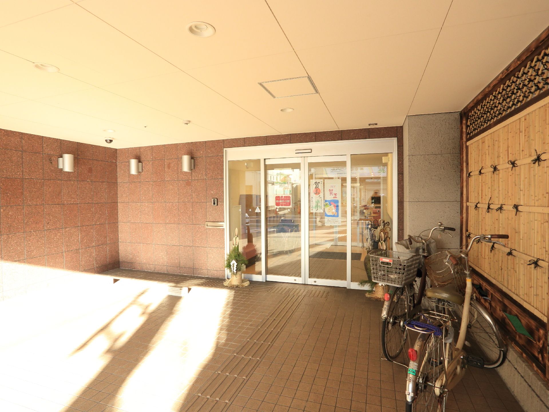 和風の施設入口には、両開きタイプのガラスサッシの自動扉が設置されており、点状、線状ブロックが完備されている。