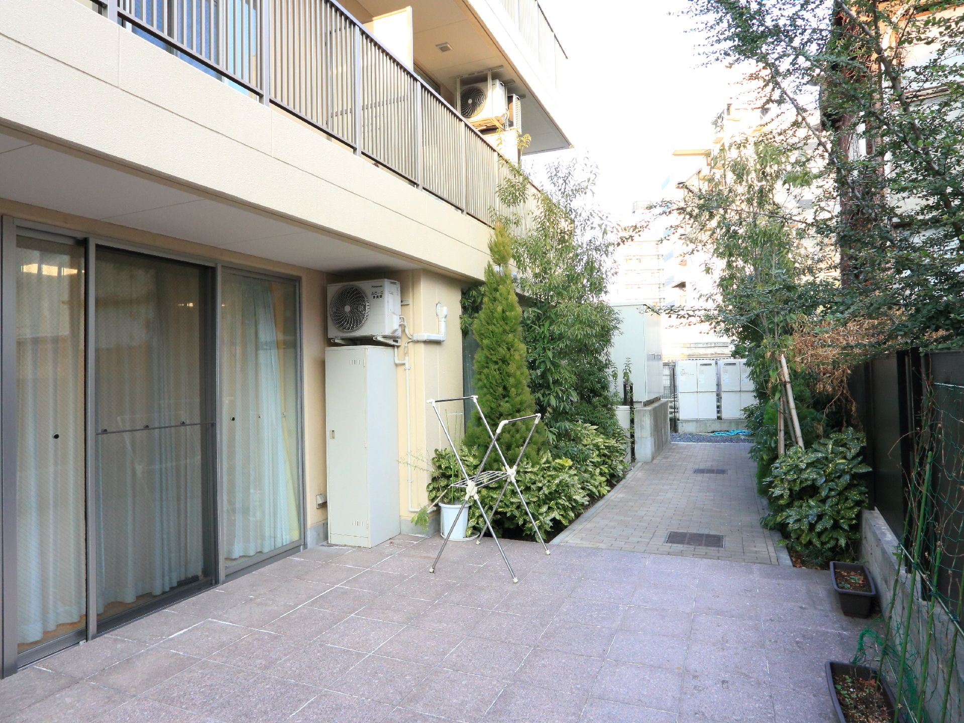 施設に完備されているテラスには、物干しラックが置かれている。通路の両サイドに植え込みがつくられ、たくさんの植物が植えられている。