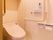 スライド式の方引き戸になっているトイレである。小物を入れる天袋が設置され、壁にはL型の手摺も設置されている。