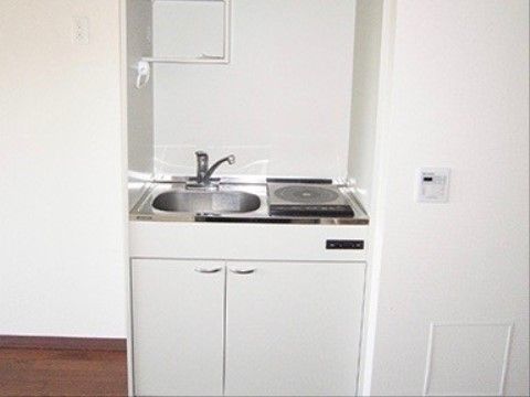 居室に設置されたミニキッチン。IHのコンロが一口とシンクがあり、シンク下は収納になっている。上部に棚とタオルハンガーがついている。