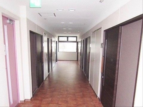 温かみのある茶色のクッションフロアが敷かれた広い廊下。突き当たりに大きな窓があり、明るい。両側にある居室のドアはスライド式になっている。