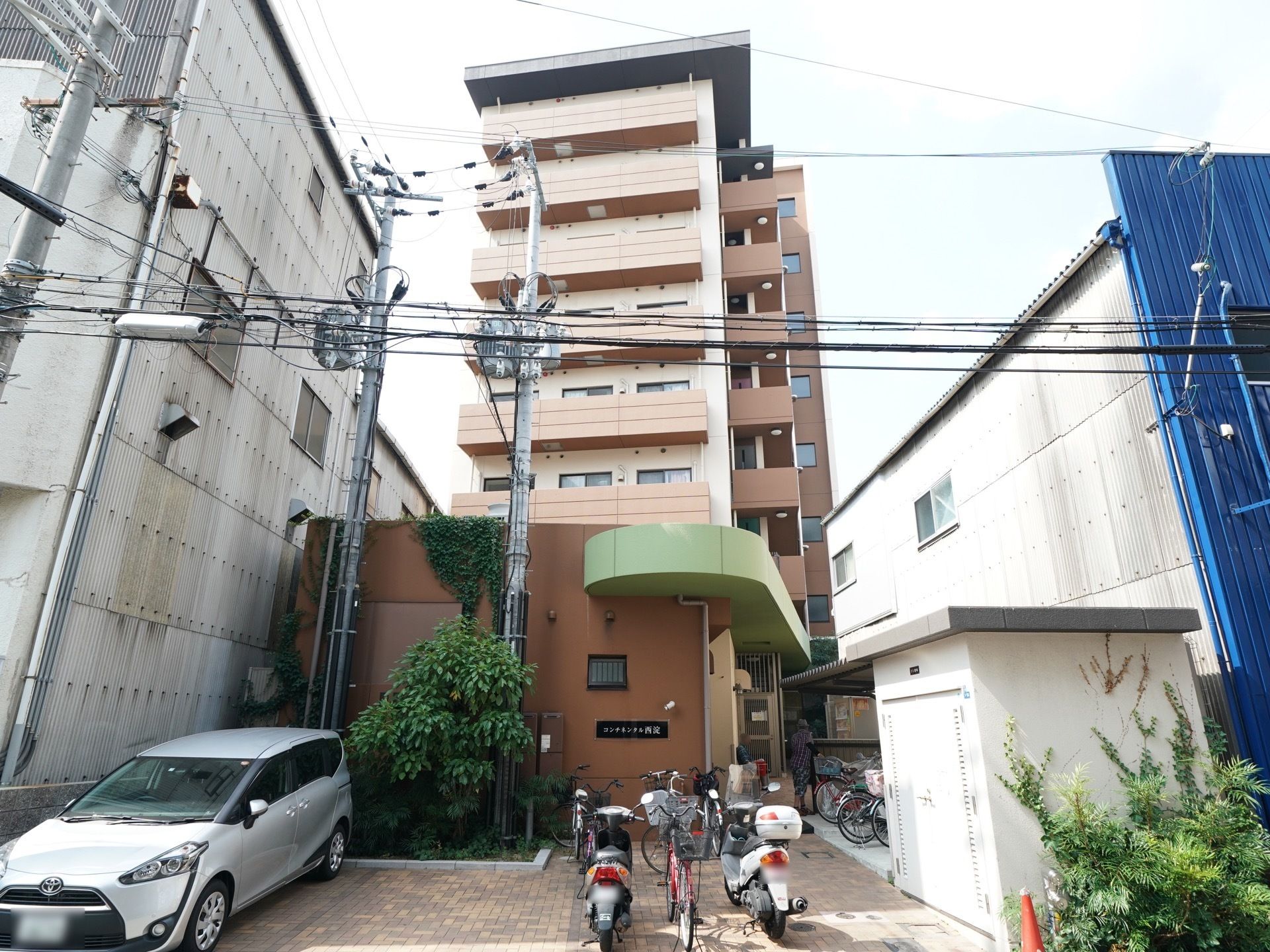 一般のマンションのような高層の建物である。施設前に車が１台止まっており、自転車や原付バイクが停められている。