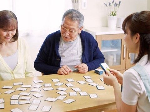 テーブルの上にカルタを広げ楽しむ三人の様子。