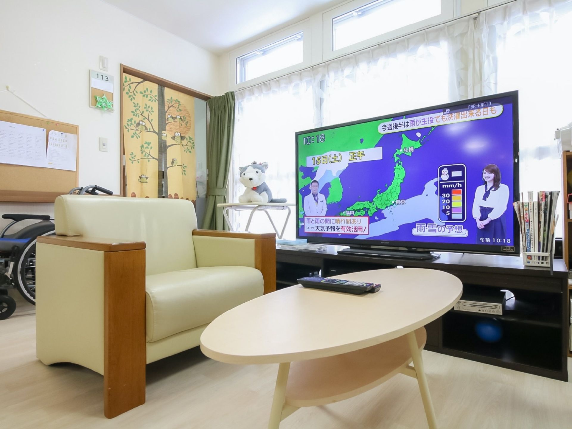 大型のテレビが設置されている。ひじが付いた椅子なので立ち上がる際に補助となる。窓から大量の光が差し込んでいる。